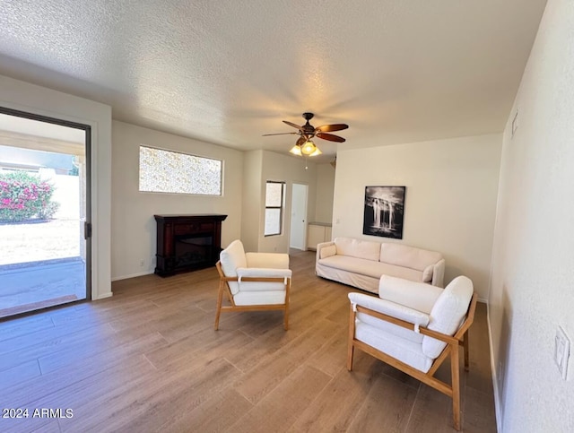 living room featuring a textured ceiling, ceiling fan, and light hardwood / wood-style flooring