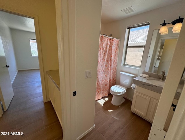 bathroom featuring walk in shower, vanity, toilet, and hardwood / wood-style flooring