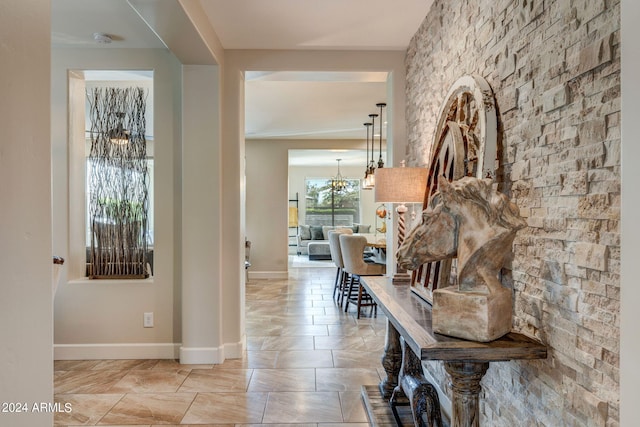 hall with a chandelier and light tile floors