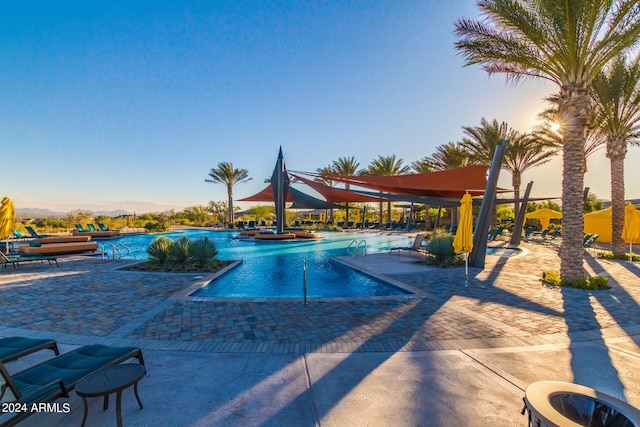 pool at dusk featuring a patio