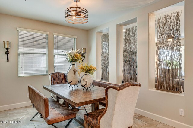 tiled dining area featuring a healthy amount of sunlight and a chandelier