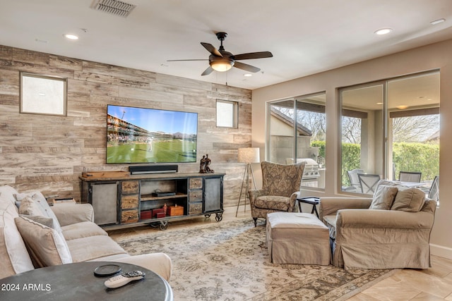 living room with light tile floors, tile walls, wood walls, and ceiling fan