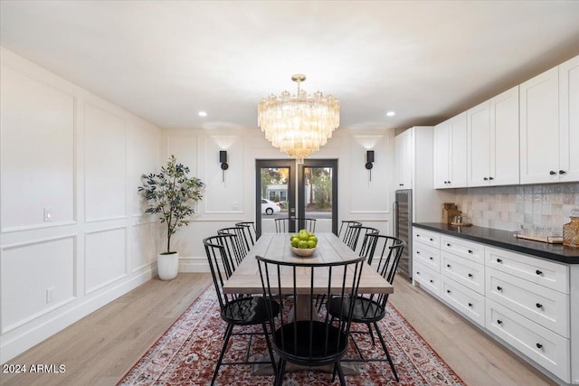 dining room featuring light wood-type flooring, recessed lighting, a notable chandelier, and a decorative wall