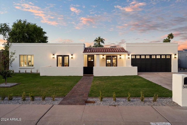 mediterranean / spanish home with stucco siding, a tile roof, driveway, a front yard, and an attached garage