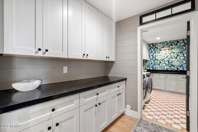 laundry room featuring washer and dryer, light hardwood / wood-style floors, and cabinets