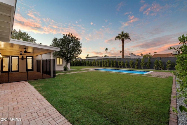 yard at dusk featuring a fenced in pool, a ceiling fan, a patio area, and a fenced backyard