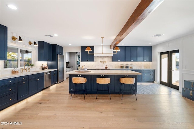 kitchen featuring beam ceiling, stainless steel appliances, light hardwood / wood-style flooring, and a kitchen island