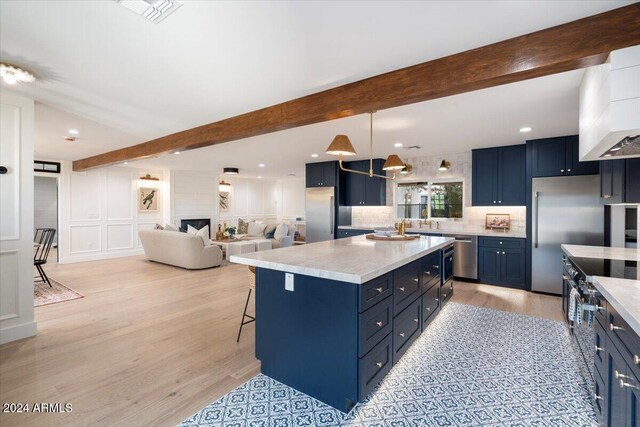 kitchen featuring beam ceiling, blue cabinets, a kitchen bar, and a kitchen island