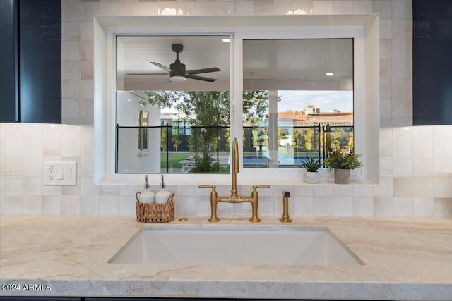 room details with ceiling fan, light stone countertops, and sink