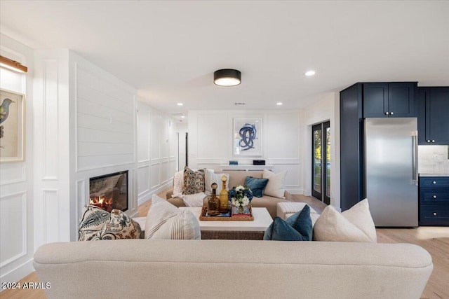 living area featuring light wood finished floors, recessed lighting, a decorative wall, and a fireplace