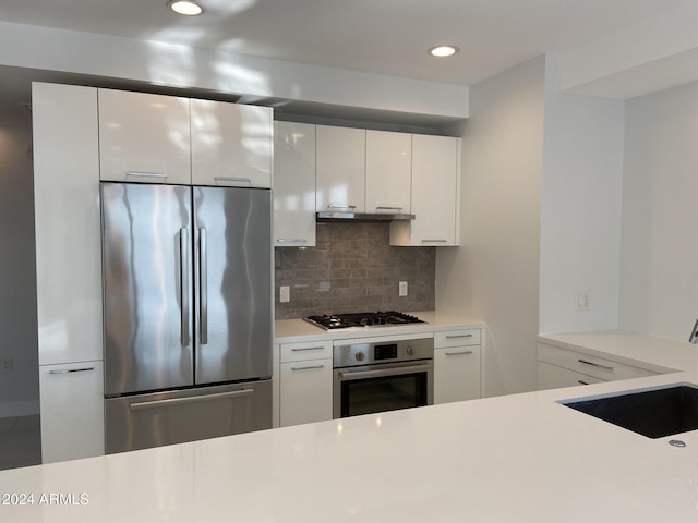 kitchen with tasteful backsplash, sink, white cabinets, and stainless steel appliances