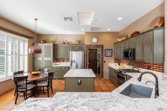 kitchen with backsplash, sink, appliances with stainless steel finishes, decorative light fixtures, and a kitchen island