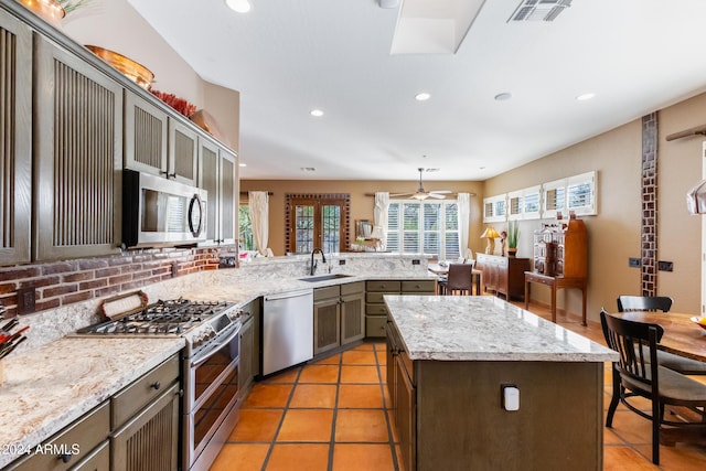 kitchen featuring ceiling fan, sink, decorative light fixtures, a kitchen island, and appliances with stainless steel finishes