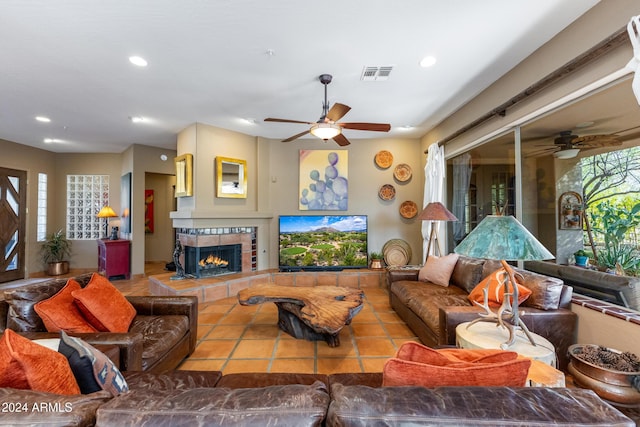 living room with a tile fireplace and ceiling fan