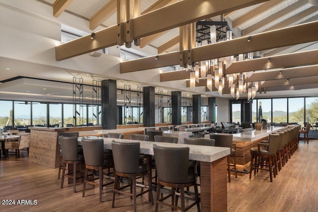 interior space featuring beamed ceiling, wood-type flooring, a breakfast bar, and high vaulted ceiling