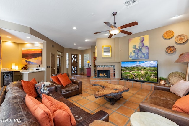 living room featuring a tile fireplace, light tile patterned floors, beverage cooler, and ceiling fan