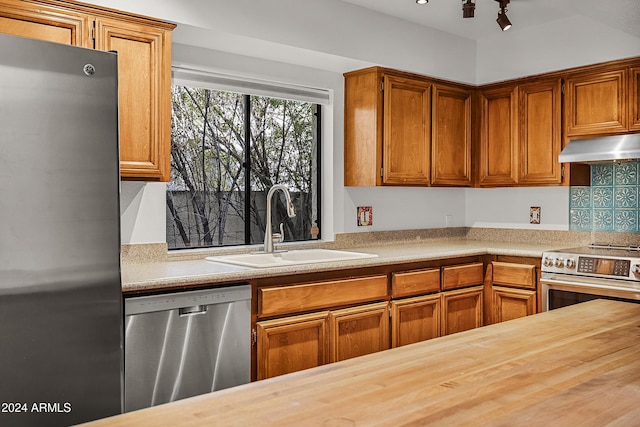 kitchen featuring sink, stainless steel appliances, wood counters, range hood, and decorative backsplash