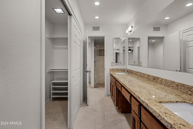 bathroom with a tile shower, vanity, and tile patterned floors