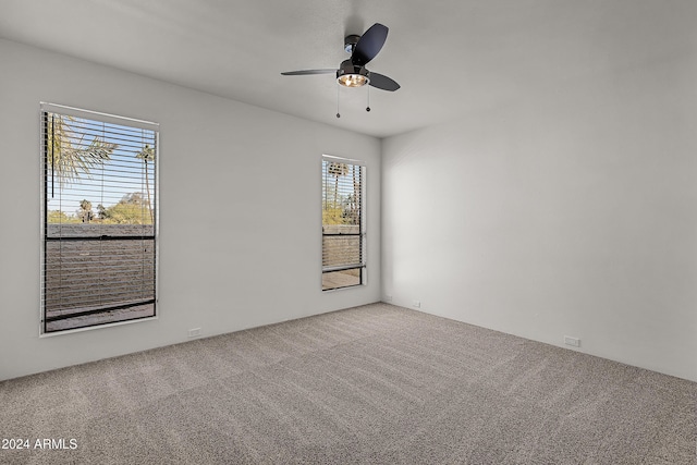 carpeted spare room featuring ceiling fan and a wealth of natural light