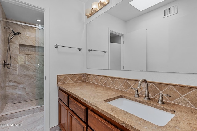 bathroom with vanity, decorative backsplash, tiled shower, and a skylight