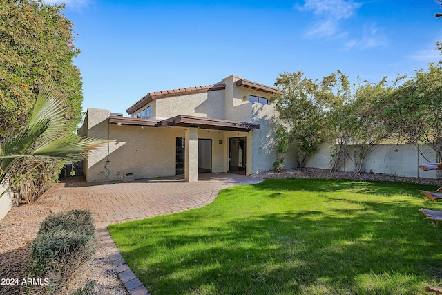 rear view of house featuring a lawn and a patio area