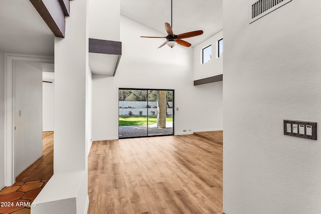 unfurnished living room featuring light hardwood / wood-style floors, high vaulted ceiling, a wealth of natural light, and ceiling fan