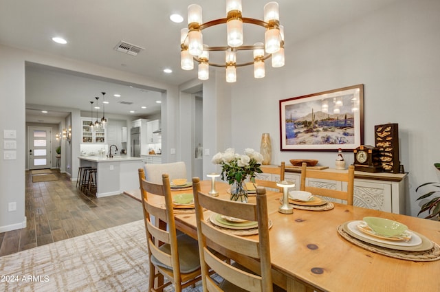 dining space featuring an inviting chandelier, sink, and dark hardwood / wood-style flooring