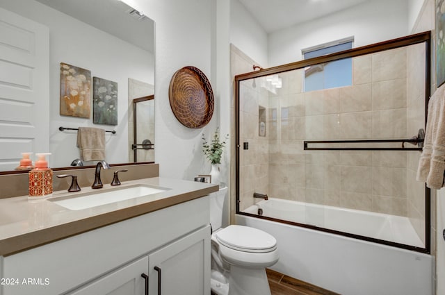 full bathroom with bath / shower combo with glass door, vanity, hardwood / wood-style floors, and toilet