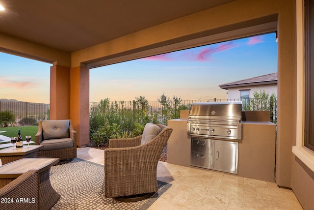 patio terrace at dusk featuring an outdoor kitchen and grilling area