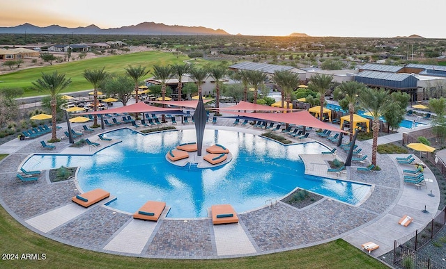 pool at dusk featuring a patio