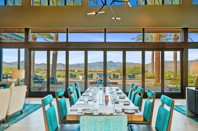 unfurnished dining area with a mountain view, plenty of natural light, a chandelier, and tile patterned floors