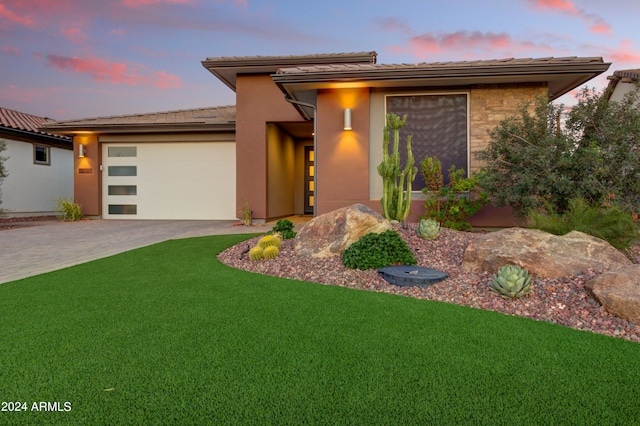 prairie-style home featuring a garage and a lawn