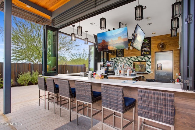 exterior space with pendant lighting, kitchen peninsula, a kitchen bar, and wooden walls