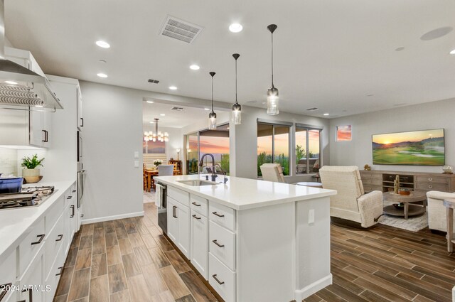 kitchen featuring an island with sink, dark hardwood / wood-style floors, sink, and white cabinetry