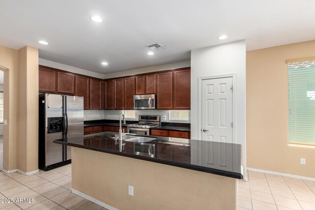 15588 W Devonshire Ave, Goodyear, AZ 85395 - kitchen featuring stainless steel appliances, light tile patterned flooring, an island with sink, dark brown cabinetry, and recessed lighting