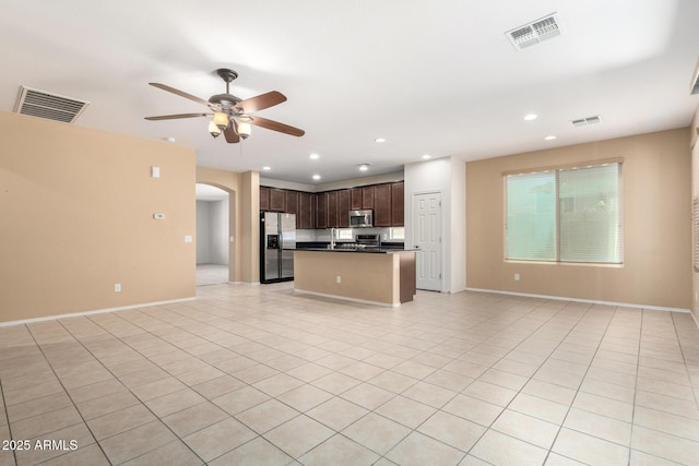 15588 W Devonshire Ave, Goodyear, AZ 85395 - kitchen featuring open floor plan, stainless steel appliances, dark countertops, ceiling fan, and arched walkways