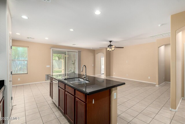 15588 W Devonshire Ave, Goodyear, AZ 85395 - kitchen featuring arched walkways, dark countertops, light tile patterned floors, stainless steel dishwasher, and recessed lighting