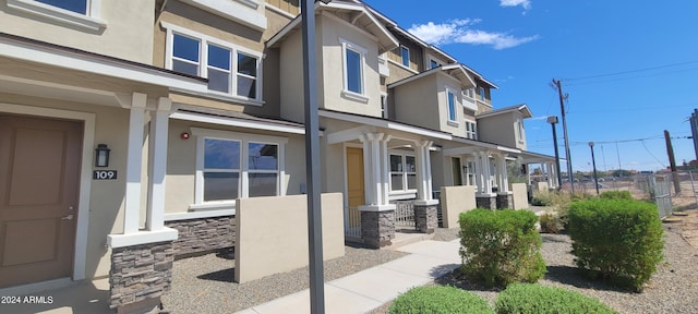 view of front facade featuring stone siding, a porch, and stucco siding