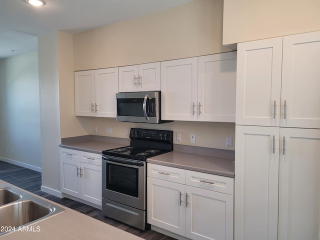 kitchen featuring dark wood-style floors, white cabinetry, appliances with stainless steel finishes, and baseboards