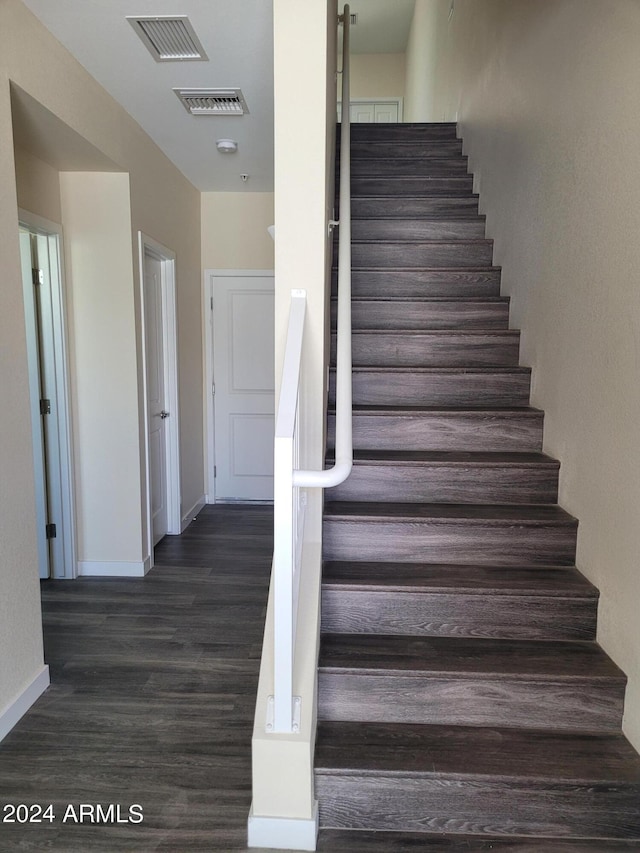 staircase featuring baseboards, visible vents, and wood finished floors