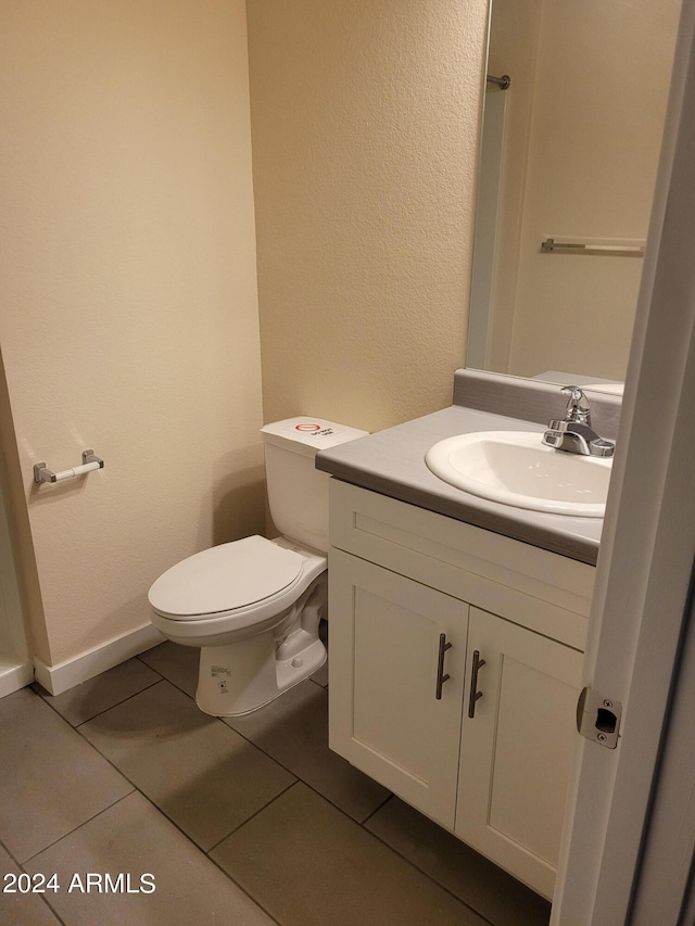 half bathroom with baseboards, vanity, toilet, and tile patterned floors