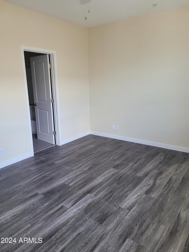 spare room featuring dark wood-style floors and baseboards