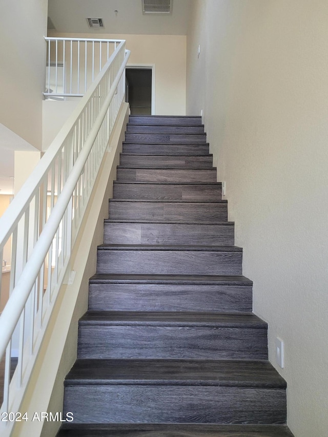 staircase featuring a high ceiling and visible vents