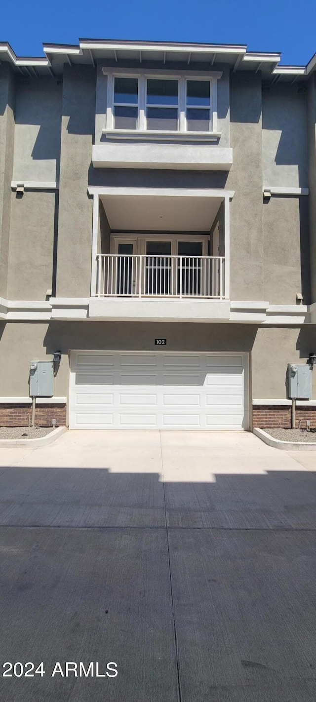 townhome / multi-family property with a garage, driveway, and stucco siding