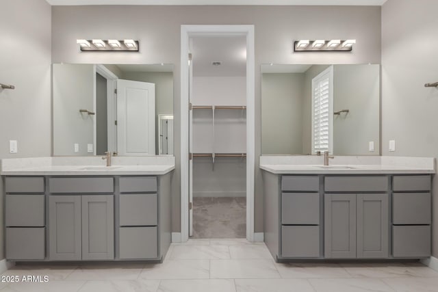 full bathroom featuring a sink, marble finish floor, and two vanities