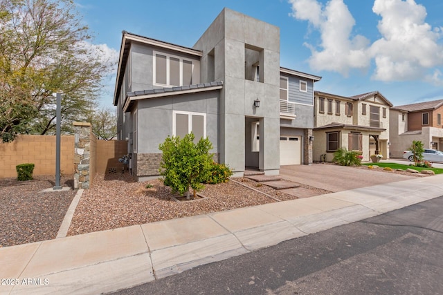 view of front of house with stucco siding, driveway, an attached garage, and fence