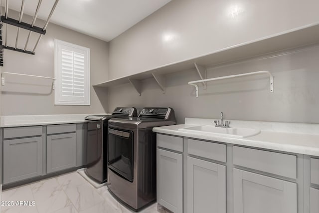 laundry area featuring a sink, cabinet space, marble finish floor, and washing machine and clothes dryer