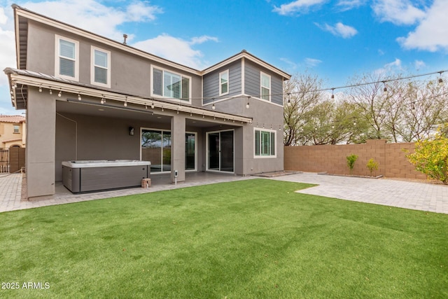 back of property featuring stucco siding, a fenced backyard, and a hot tub