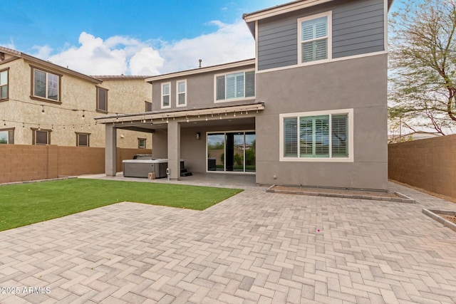 back of property featuring stucco siding, a patio area, a fenced backyard, and a hot tub