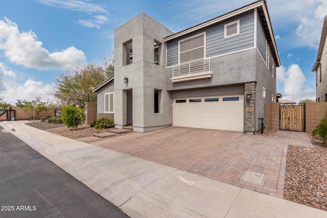 modern home with a balcony, a gate, stucco siding, a garage, and decorative driveway